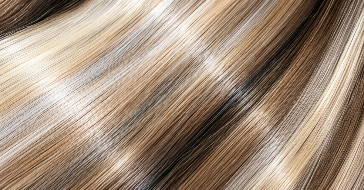 Close-up of multi-toned brown and blonde hair strands flowing diagonally across the frame